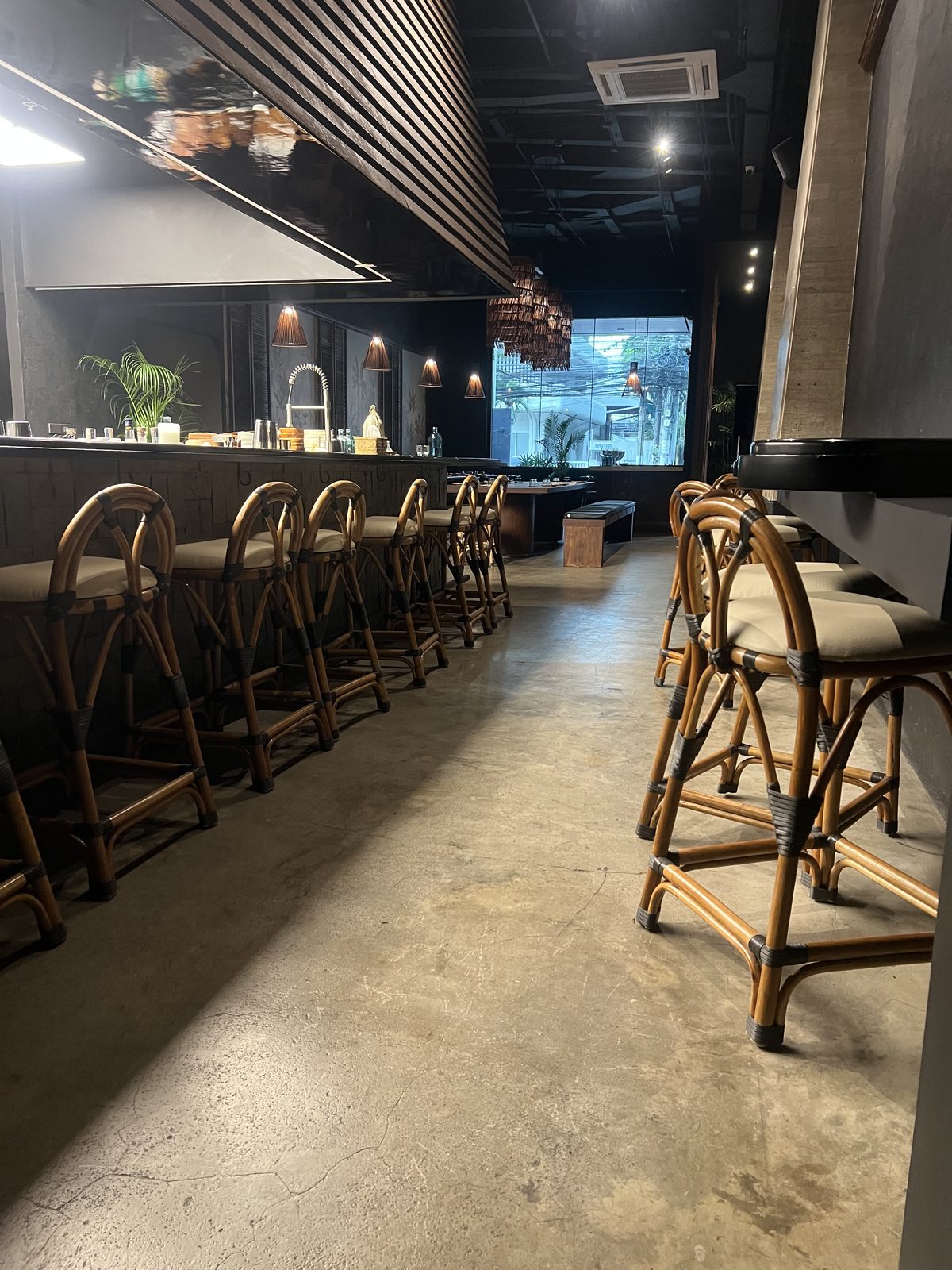 Rows of rattan bar stools lining the service counter and high tables at Toma Toma, Makati